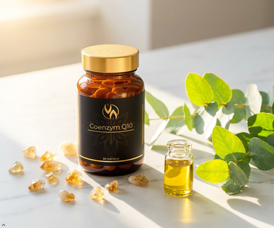 Coenzym Q10 Kapseln in Glasflasche mit goldenem Deckel, umgeben von Eukalyptusblättern und natürlichen Kristallen